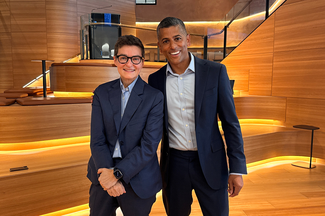 Two guest speakers photographed together in a modern auditorium-style space with timber-lined walls and tiered seating at the Future Fund’s Melbourne office.