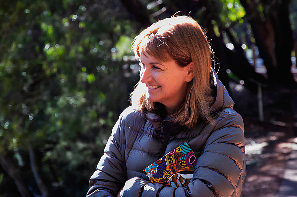 Person standing outdoors at a worksite, reviewing information while visiting a regional location.